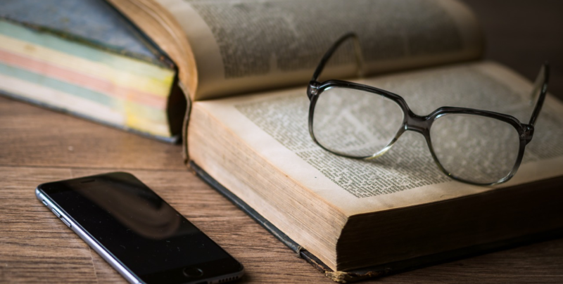 Open book, glasses, and phone